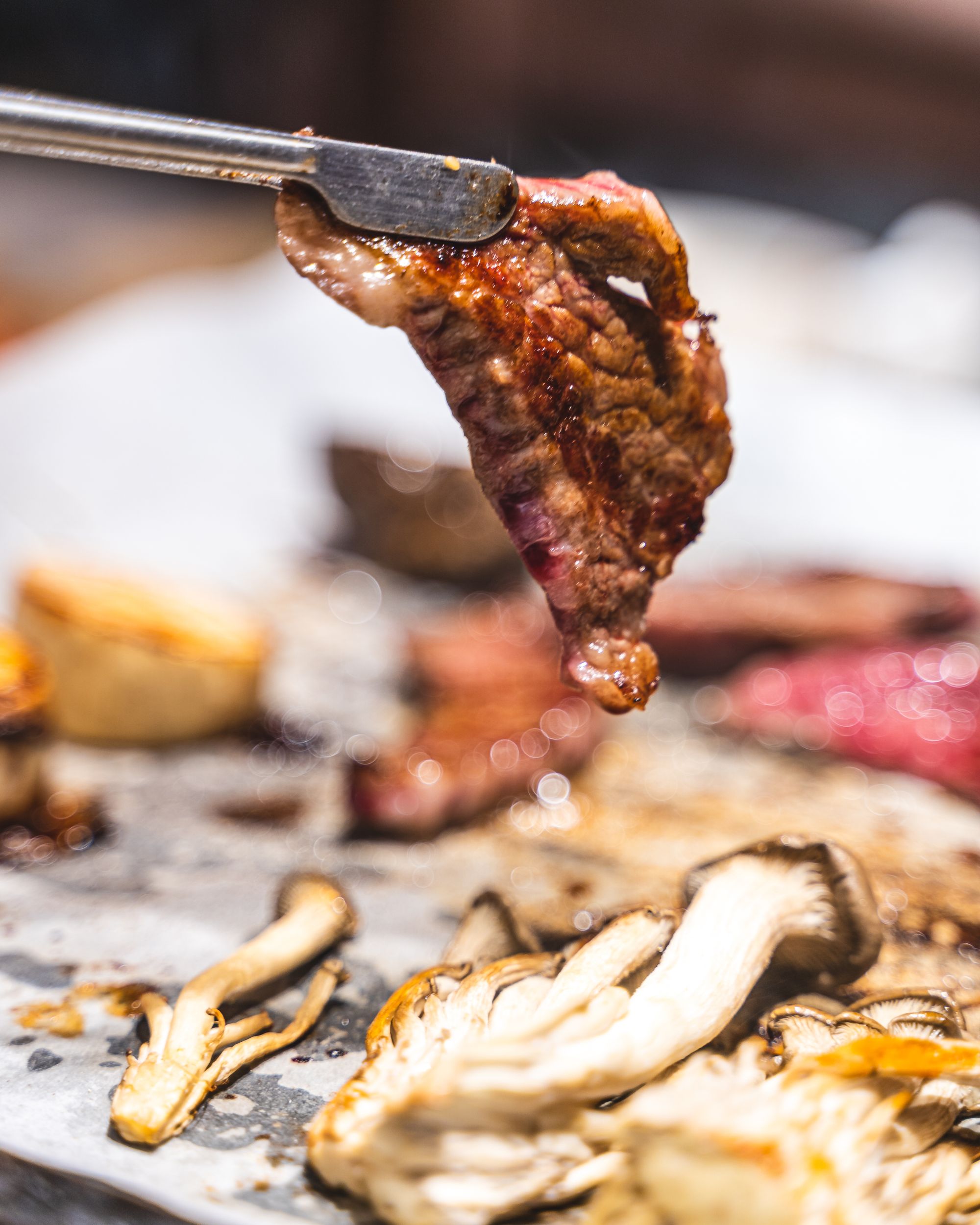 A close up shot of grilled meat being held with tongs