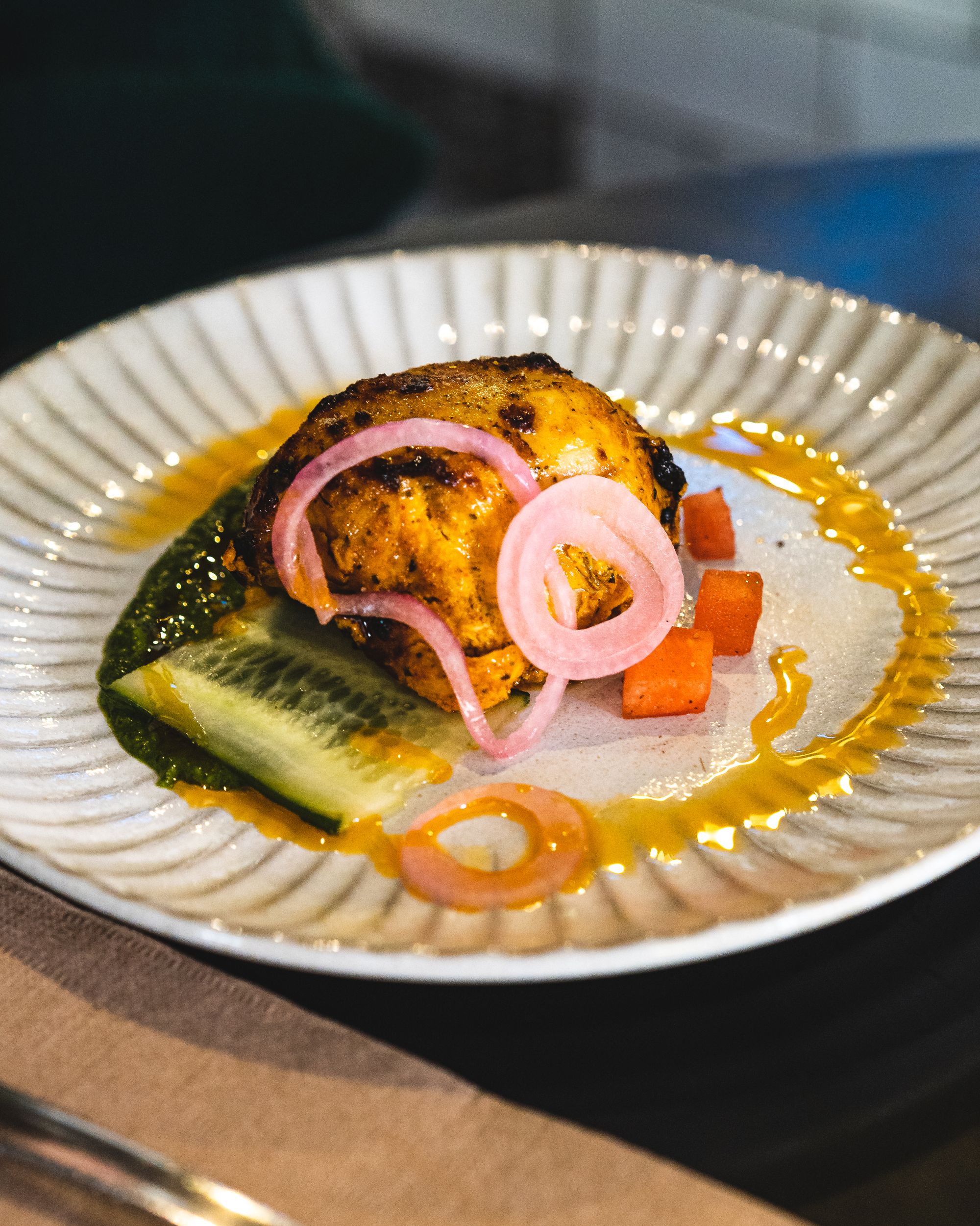 Close up shot of chicken tikka with tomato, onion and cucumber as garnish