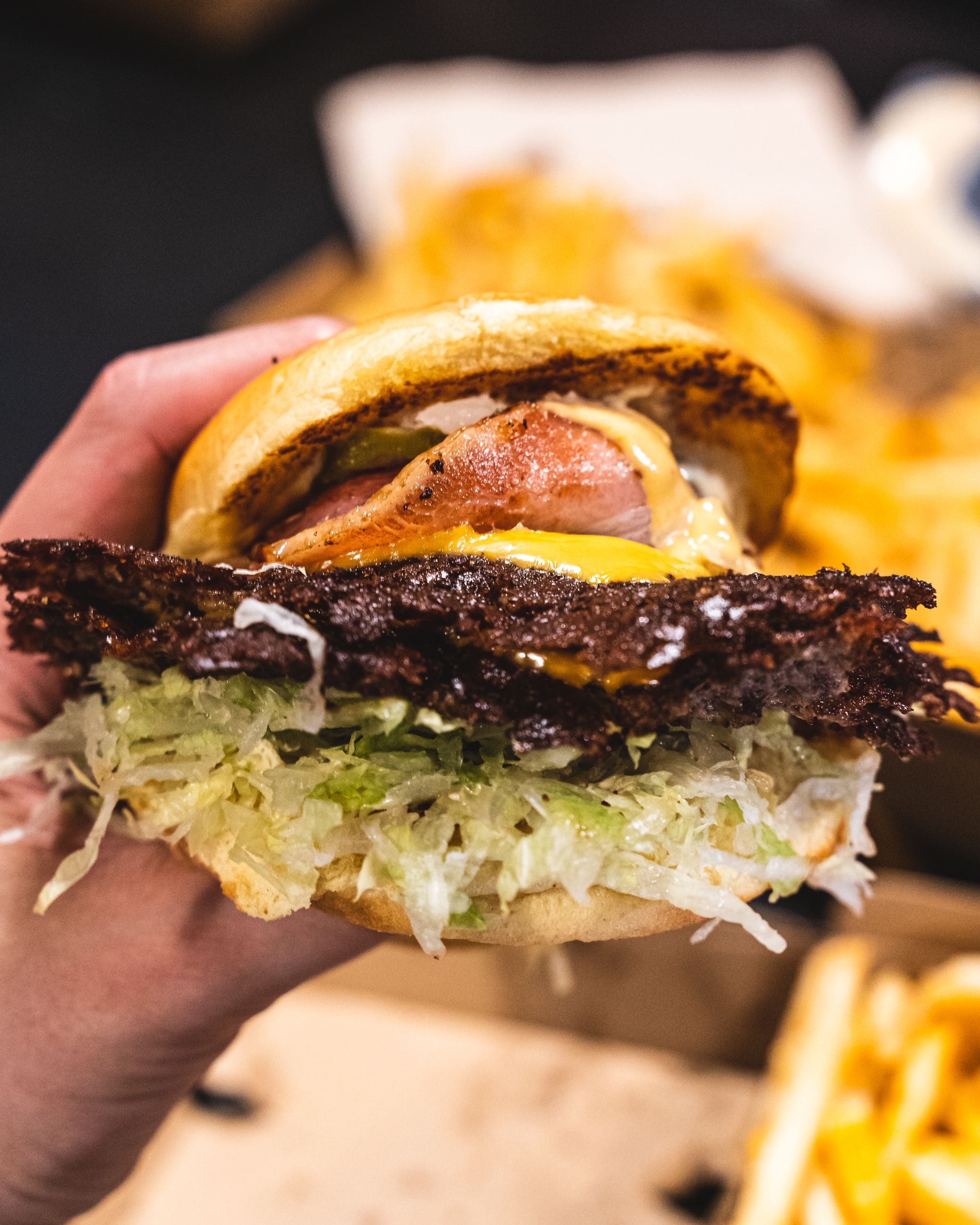 Close up of a smashed burger showing crispy beef patty edges, bacon and lettuce 