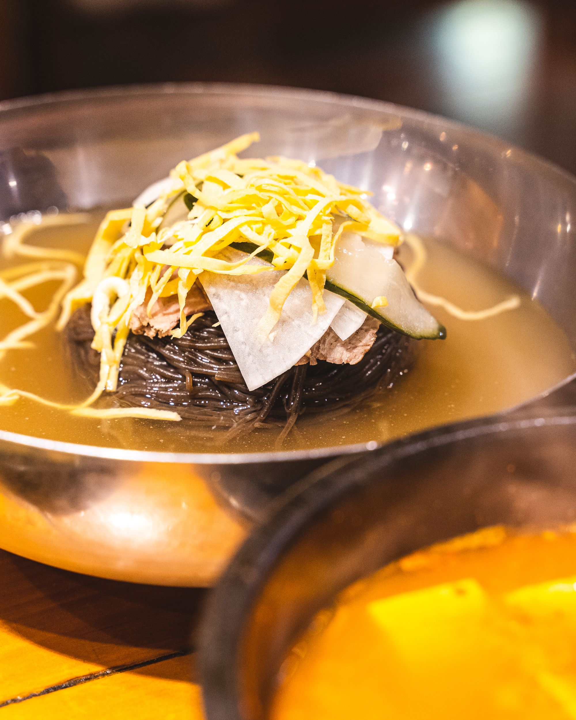 Close up of cold Korean noodles, with sliced egg and raddish on the top