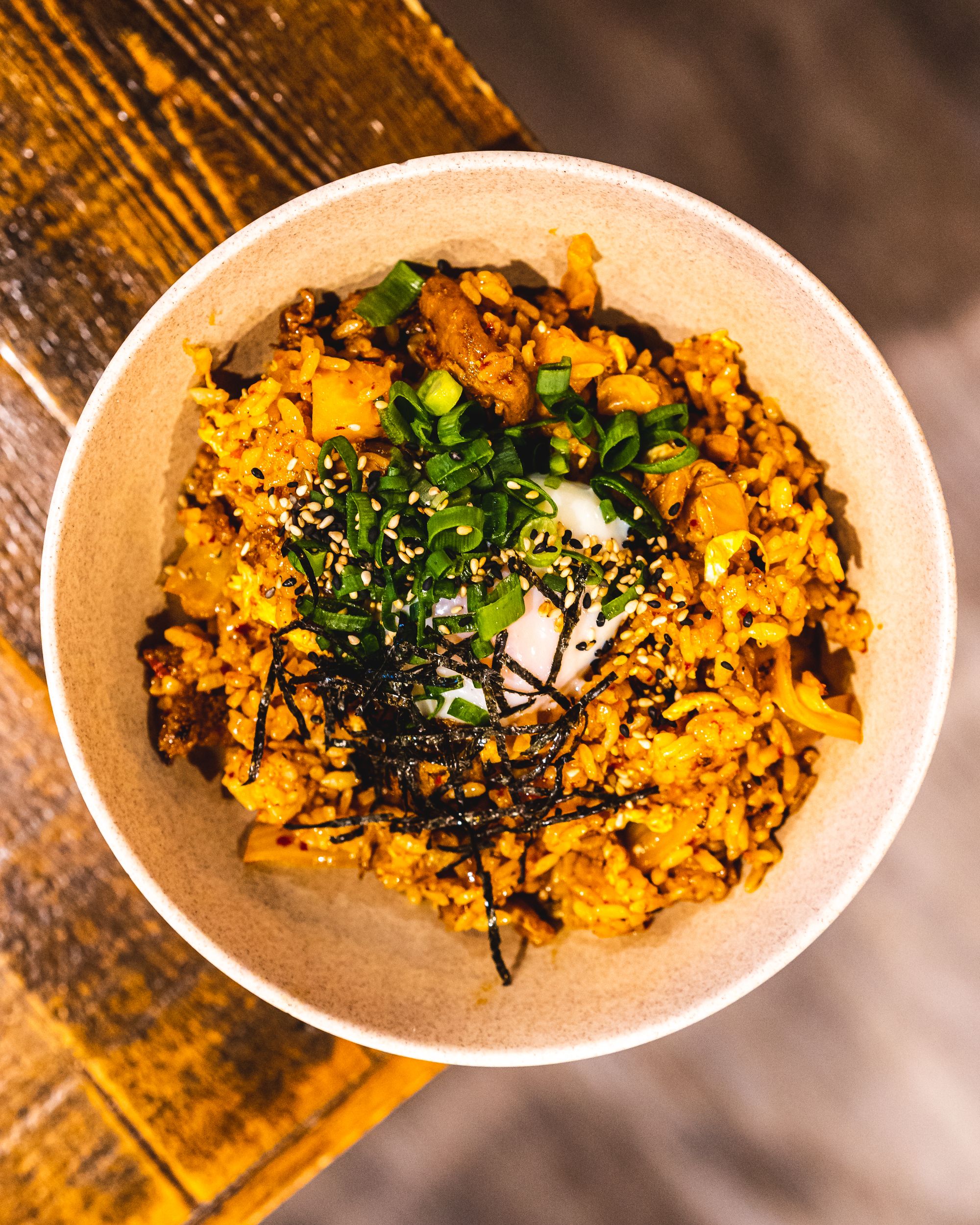 Overhead shot of kimchi fried rice, with a sous vide egg, seaweed and spring onion as garnish