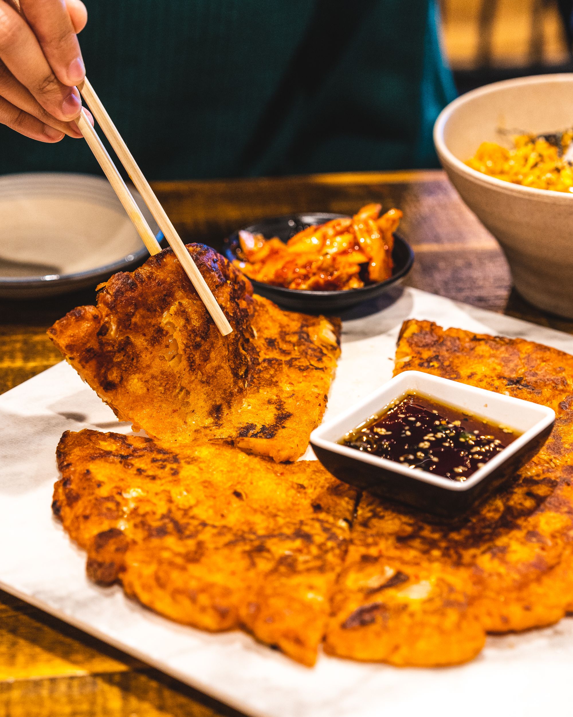 Close up shots of chopsticks picking up Korean kimchi pancake