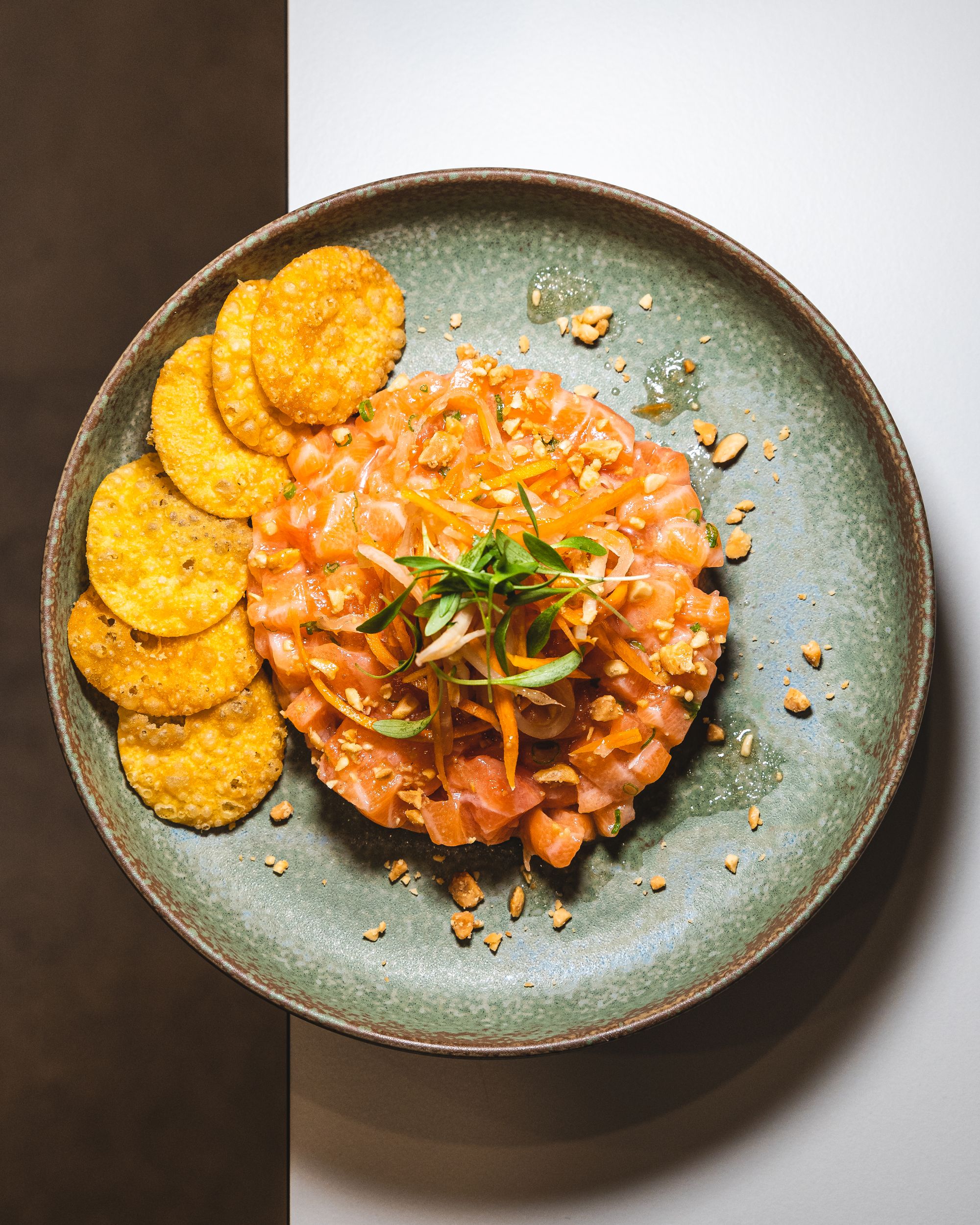 Salmon sashimi diced on a plate arranged in a circle with crisps on the side