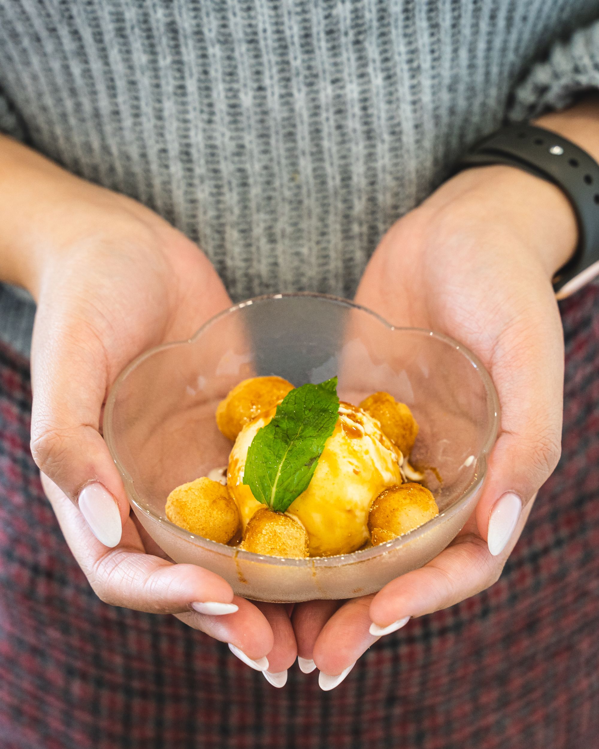 Pedicured hands holding a bowl of mochi with brown rice