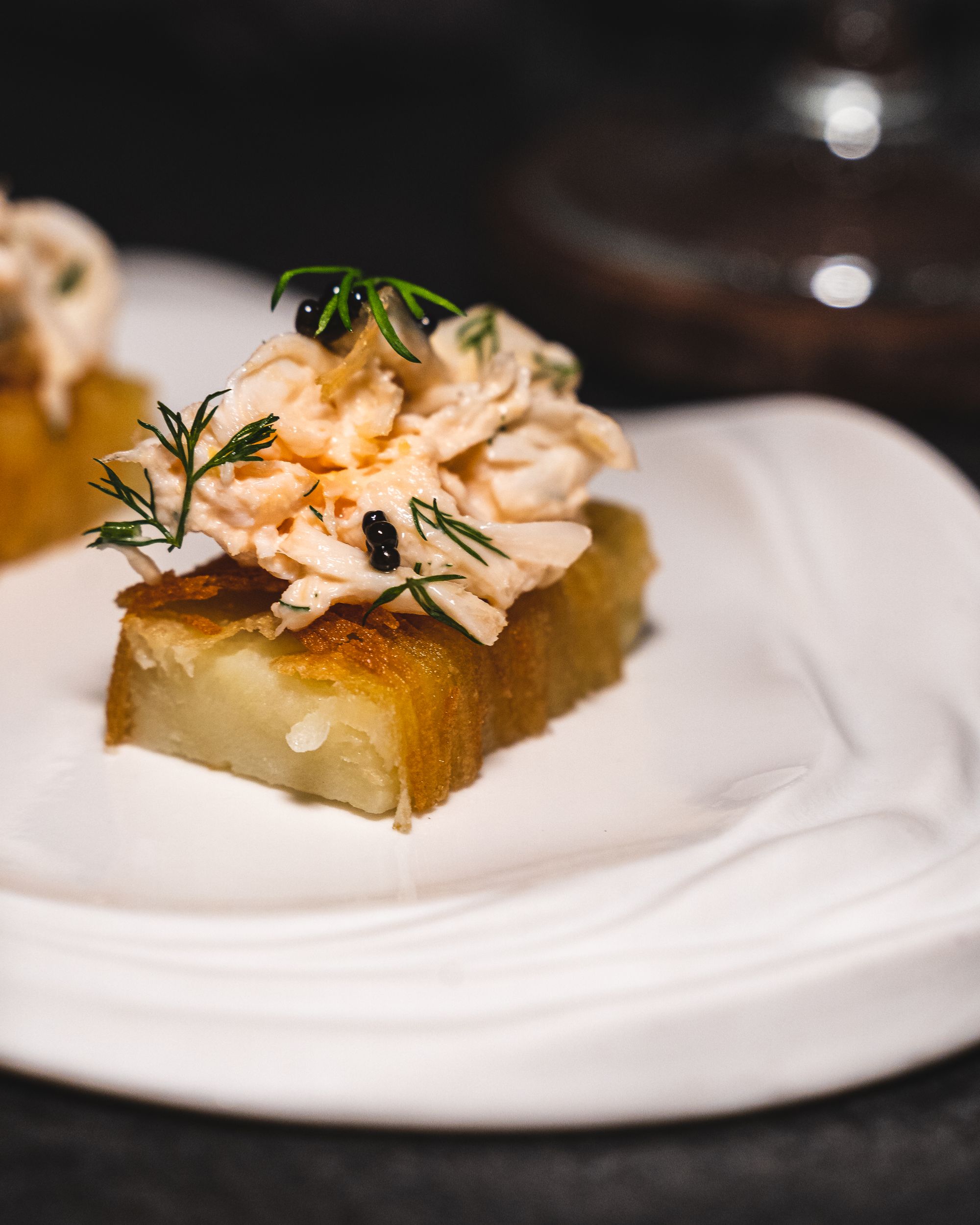 Close up of lobster meat and caviar on a slab of fried potato