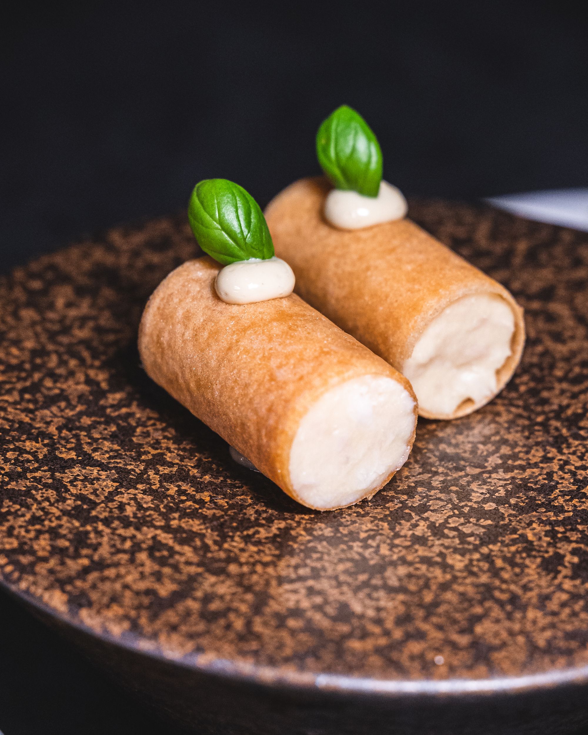 Close up of two mini cannoli with basil and oyster mayonnaise on the top