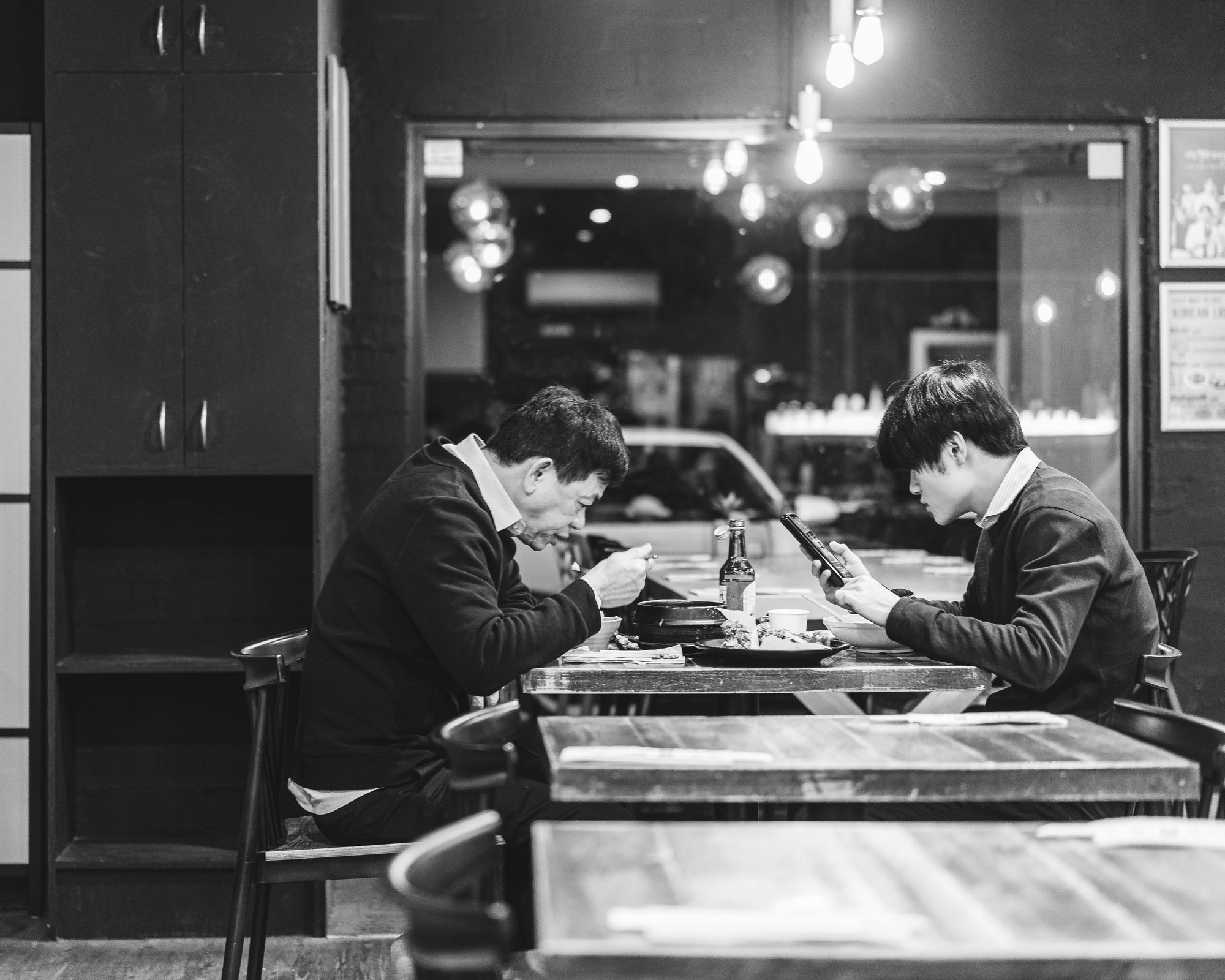 Black and white photo of wwo men eating food in a restaurant