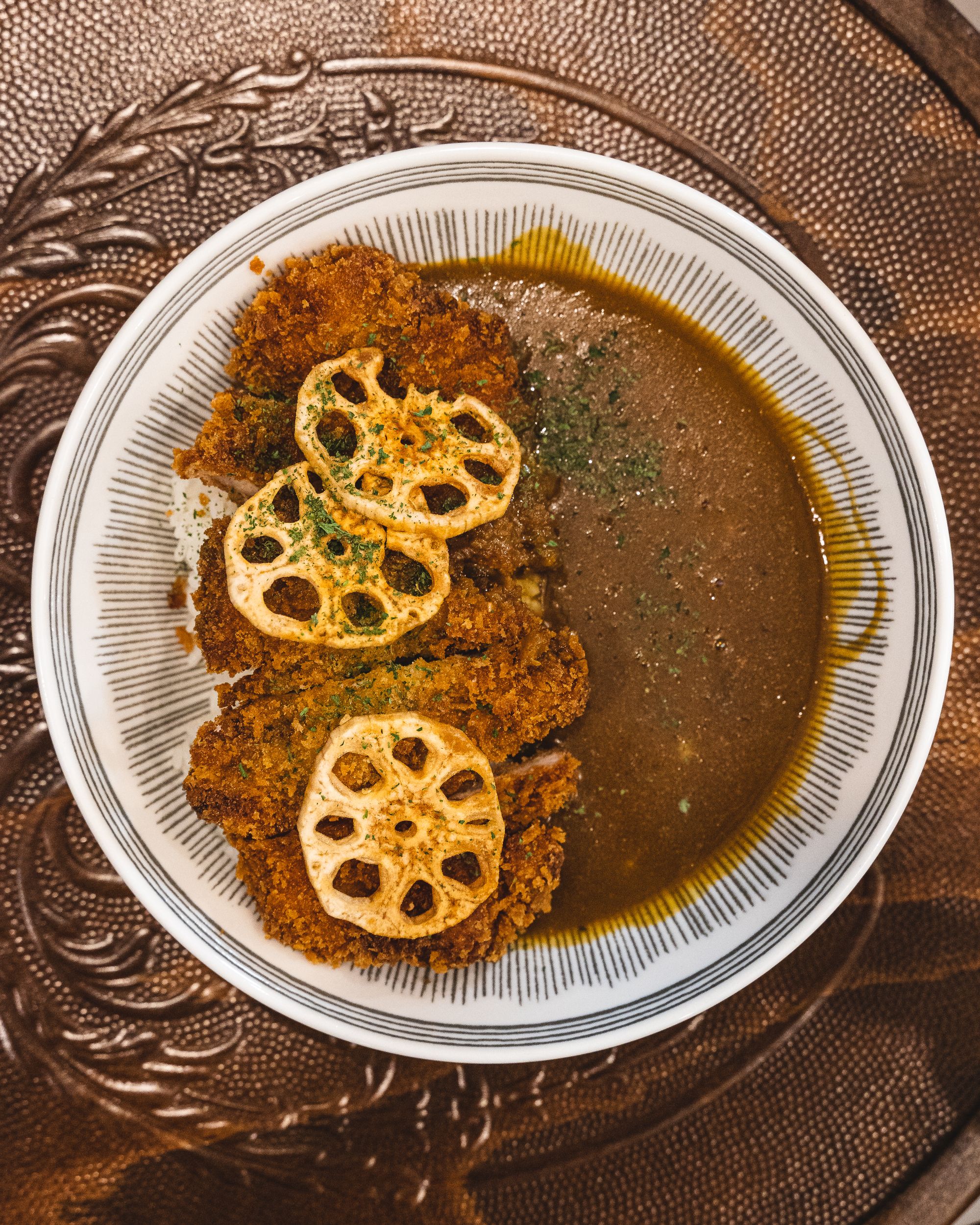 Overhead shot of Japanese curry with chicken katsu and fried lotus chips
