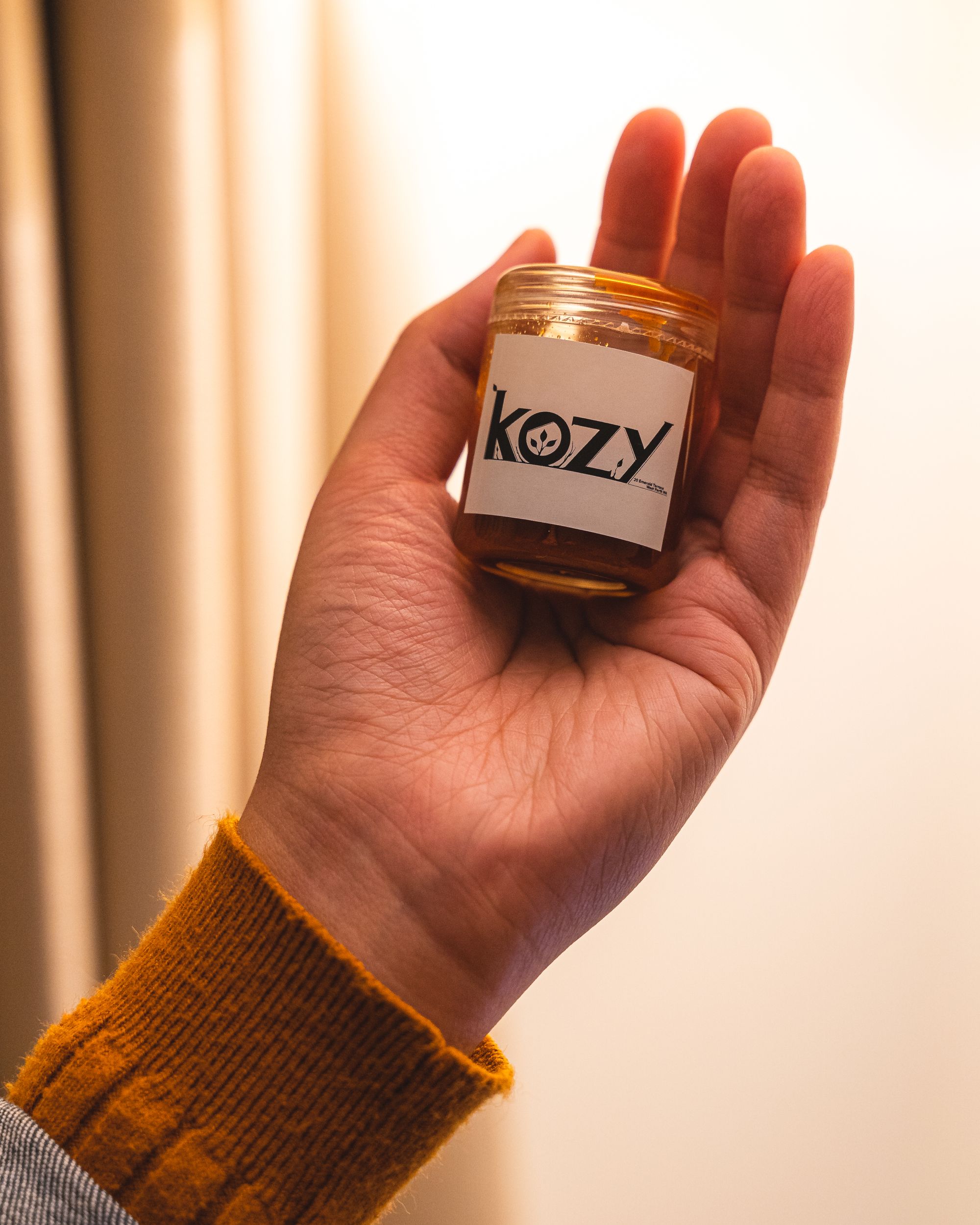 Hand holding a container of sauce with "Kozy" written on it