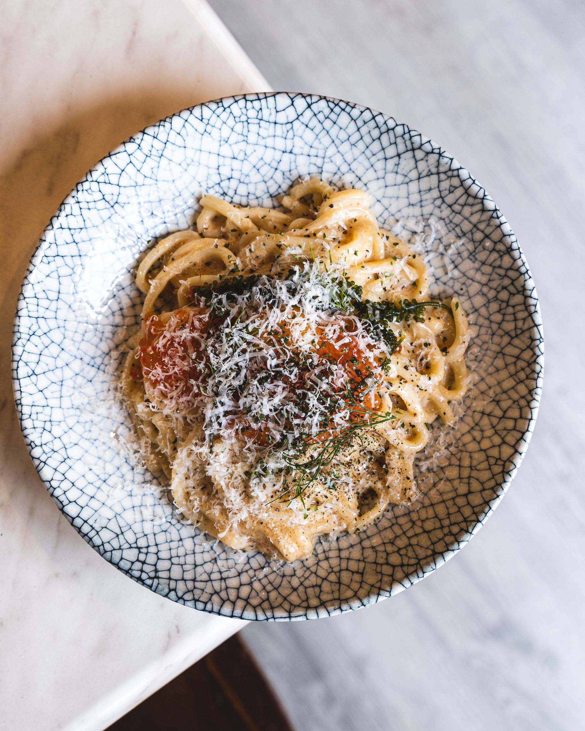 Top down of creamy udon with shaved cheese and ikura on top