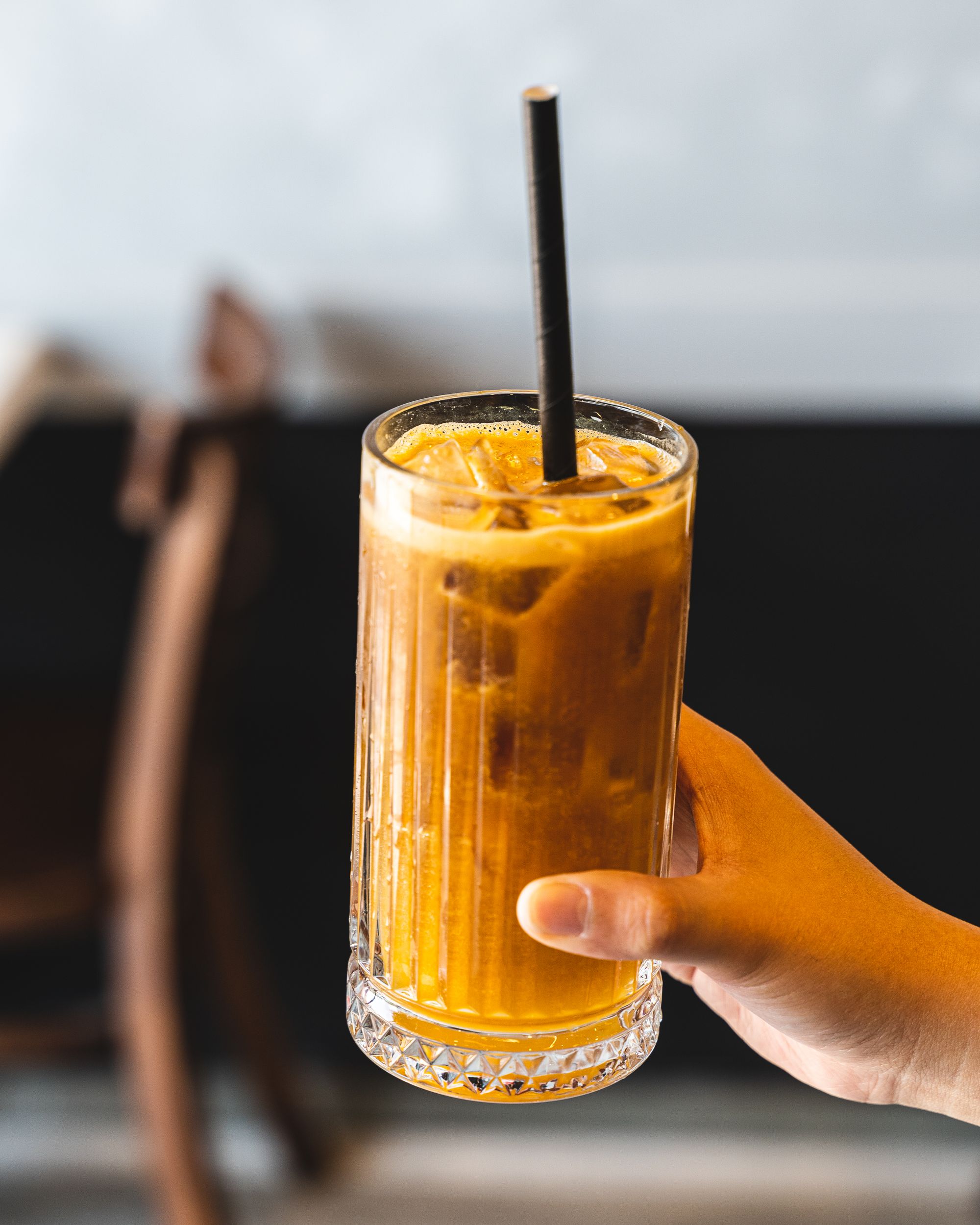 Hand holding coffee in a tall glass