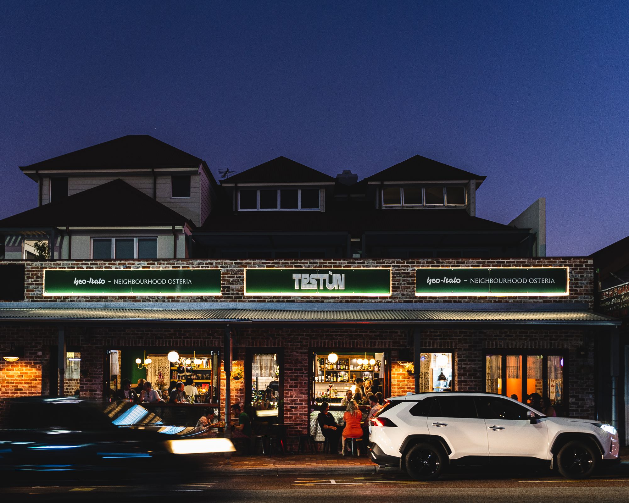 Exterior of Testun with cars parked out front