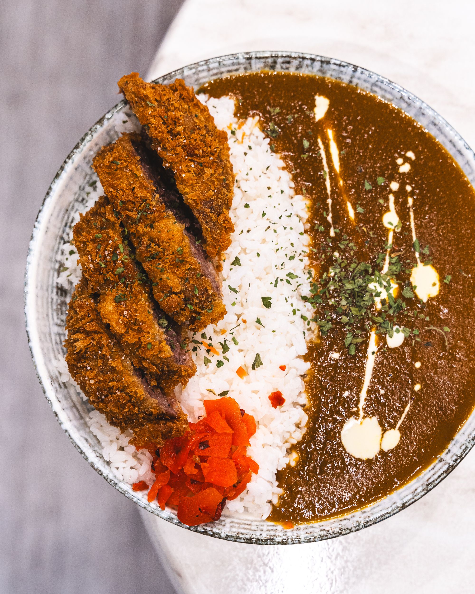 Top down shot of katsu, rice, pickled raddish and curry sauce