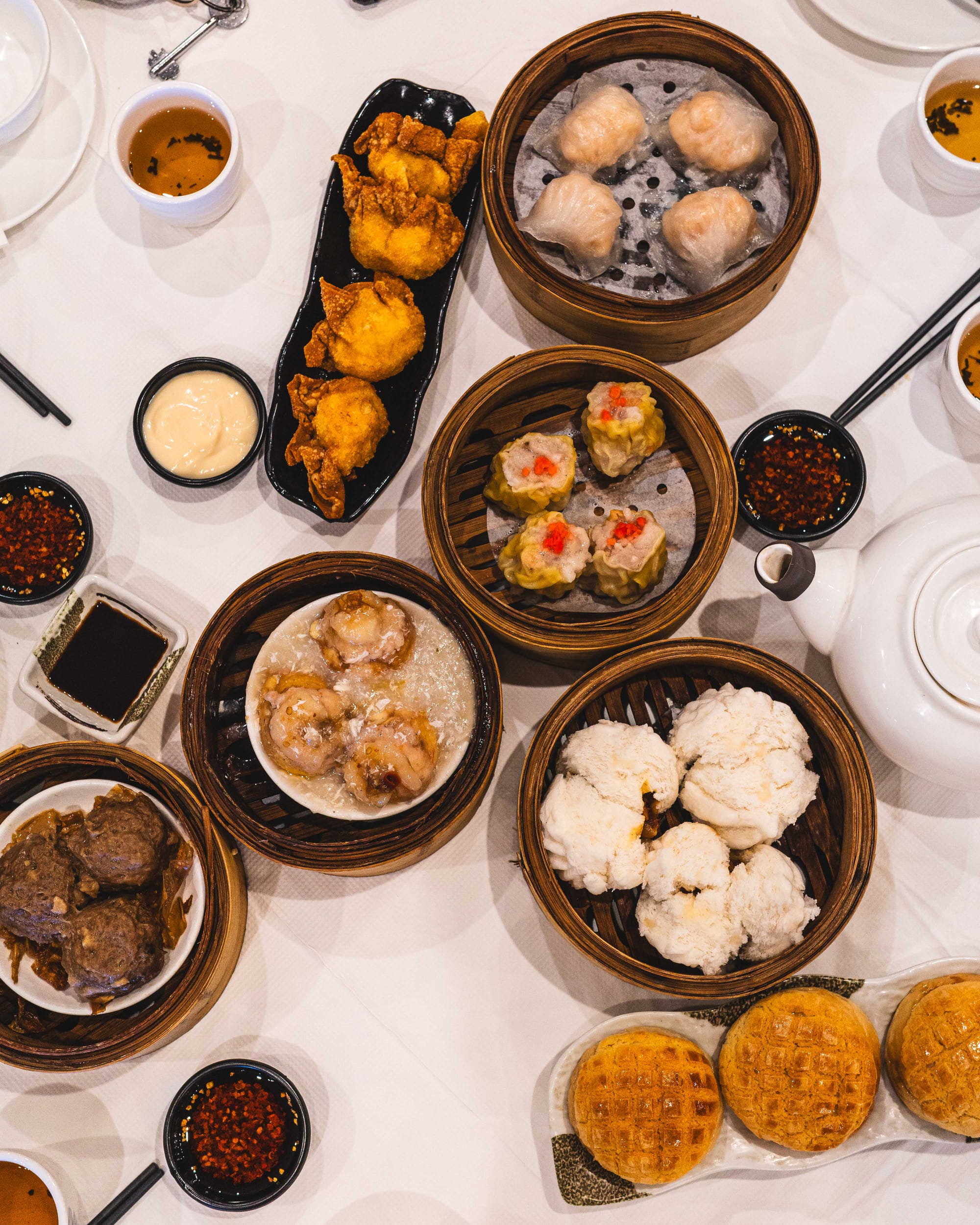 Top down shot of dim sum dishes on a white tablecloth