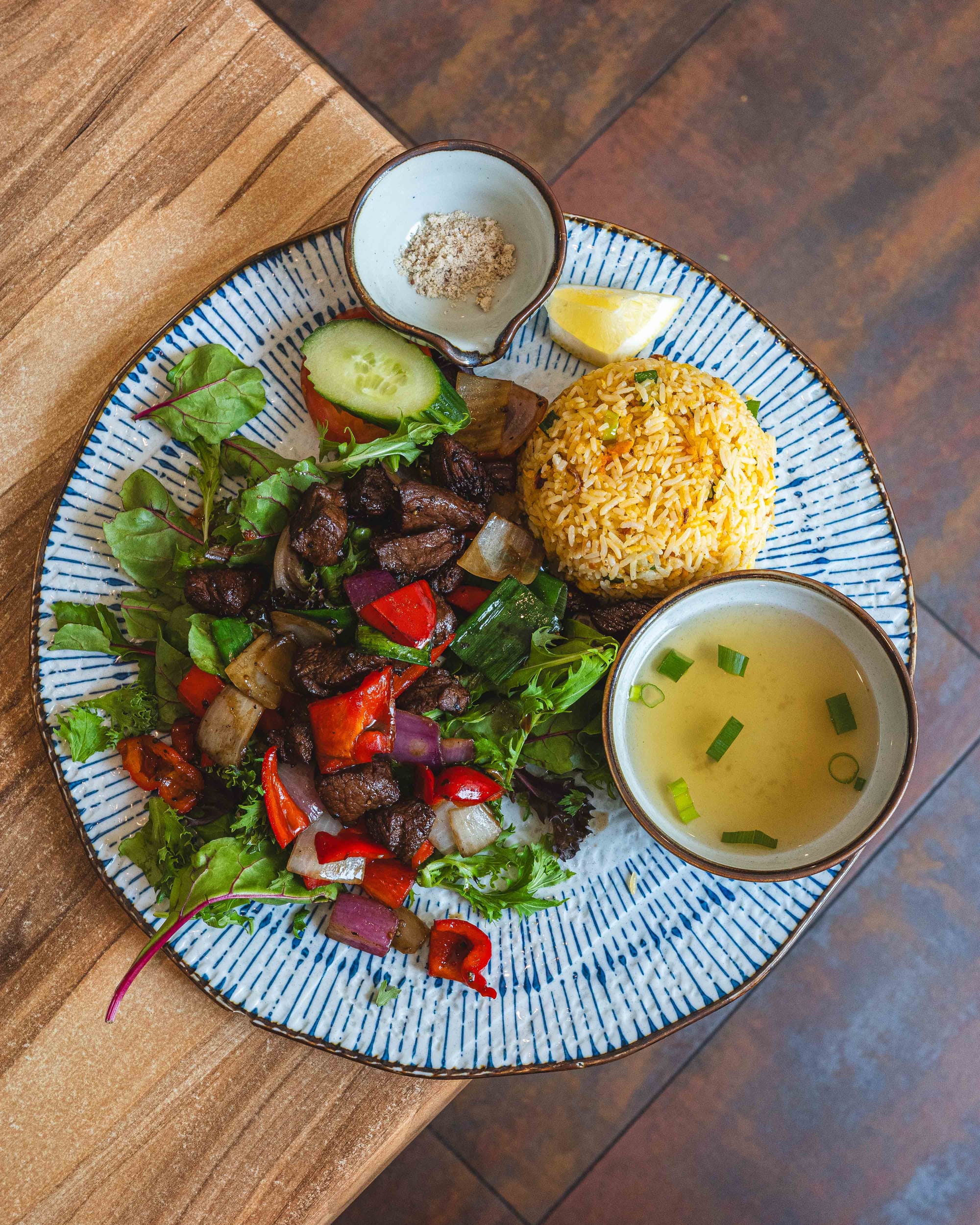 Top down shot of stir fried beef with colourful vegetables, rice and soup