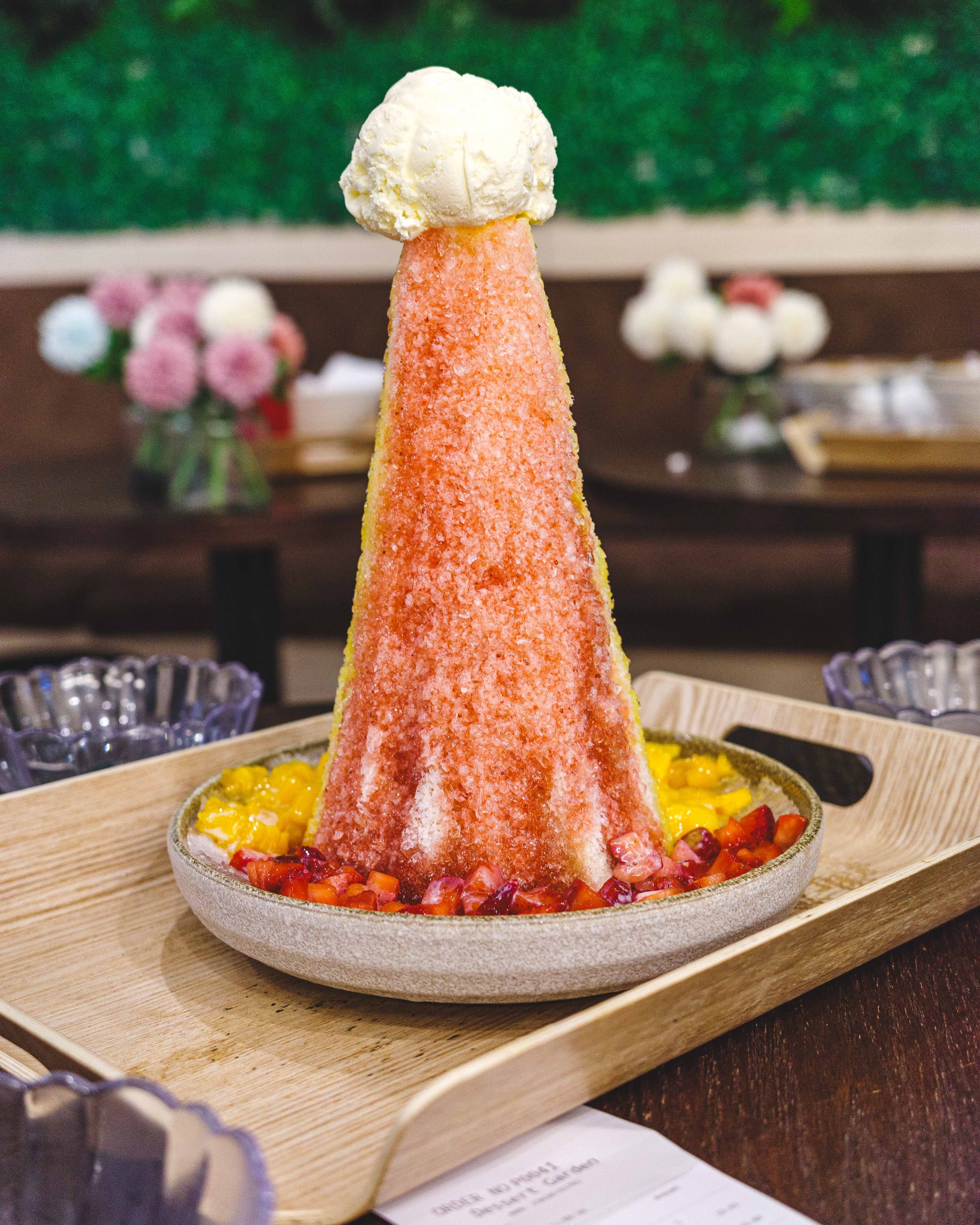 Cone shaped coloured tower made from ice with a scoop of ice-cream on top