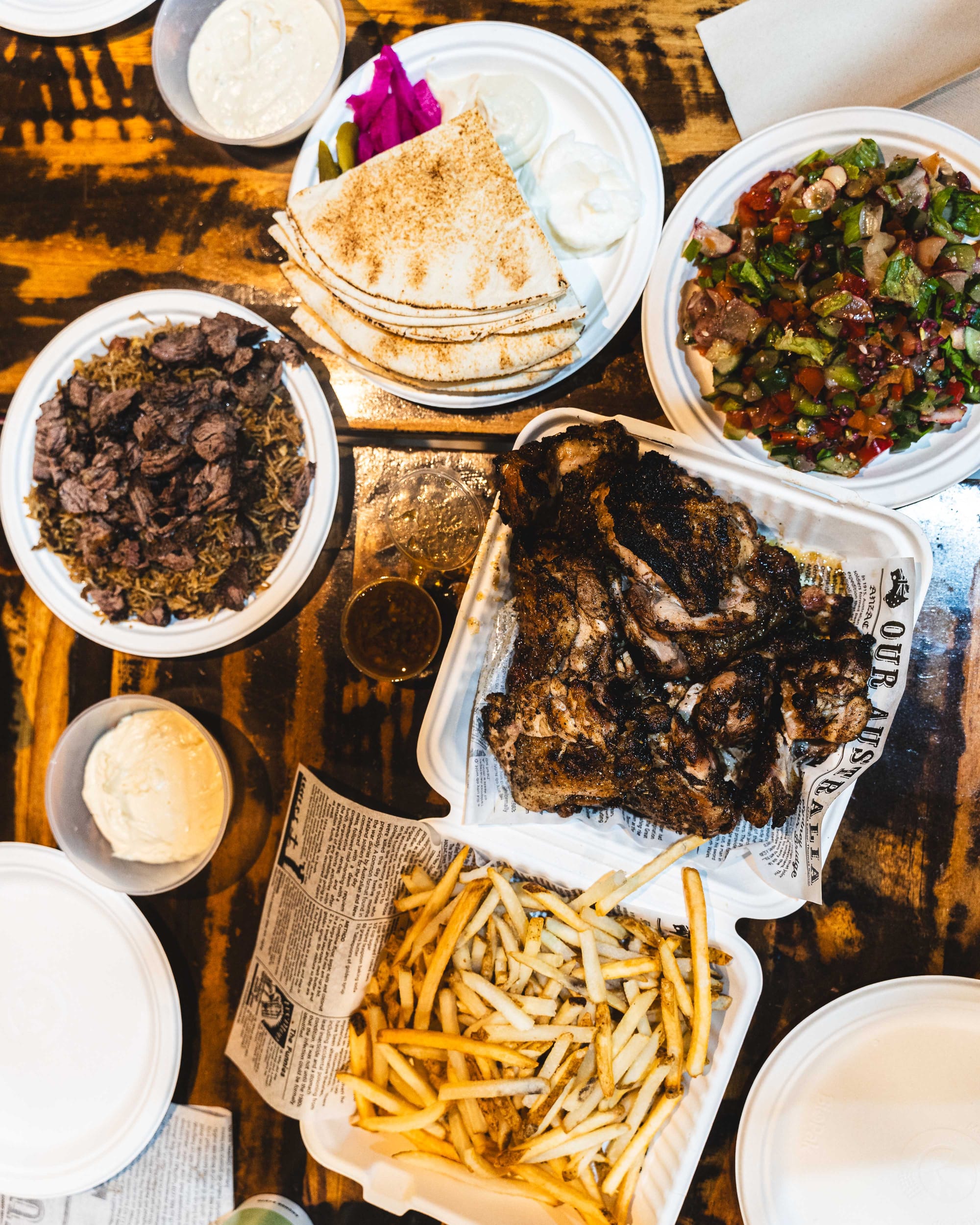 Top down shot of flat lay comprising of grilled chicken, shoestring fries, salad, Lebanese bread and rice
