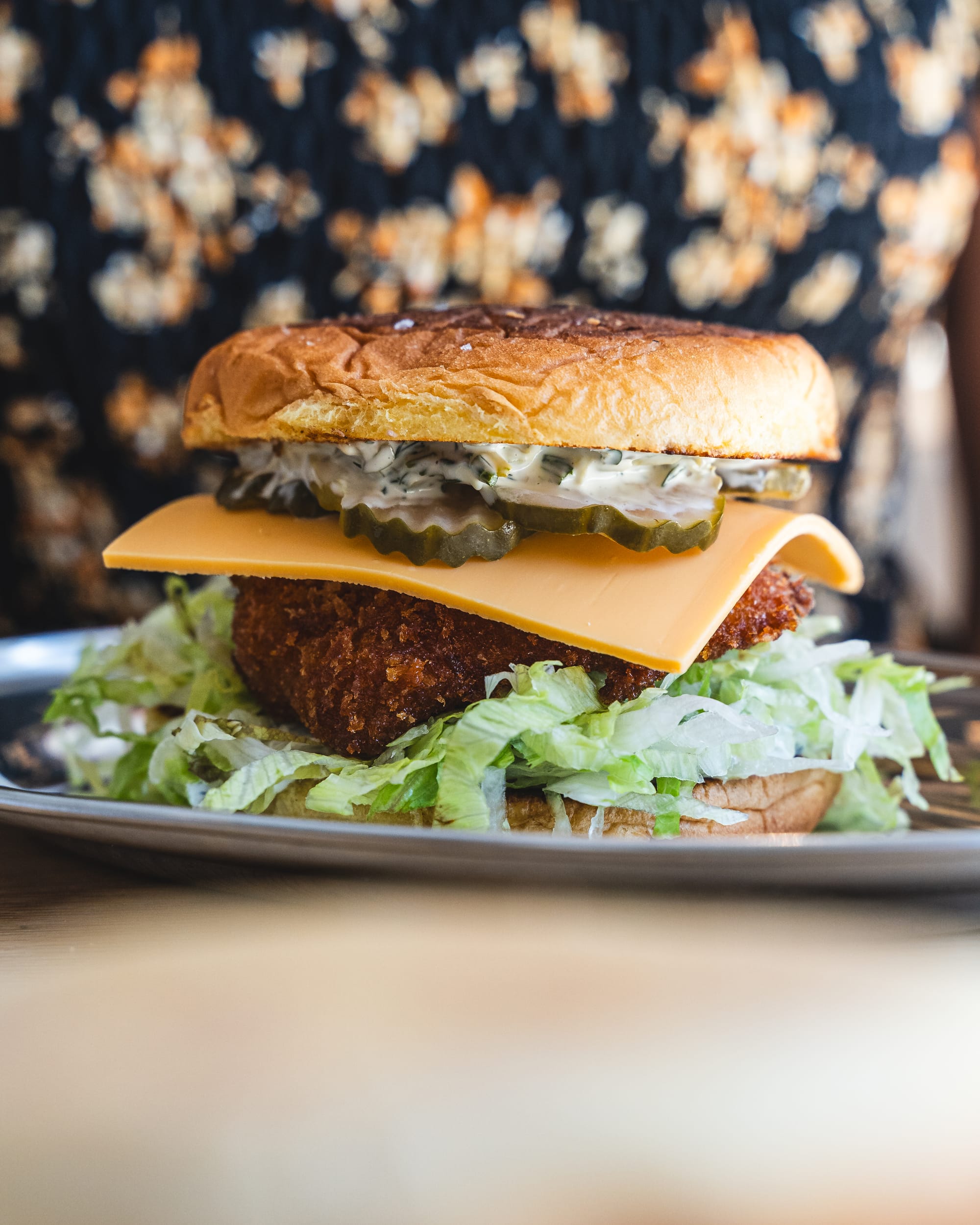 Close up of fish sandwich with pickles, lettuce and cheese showing