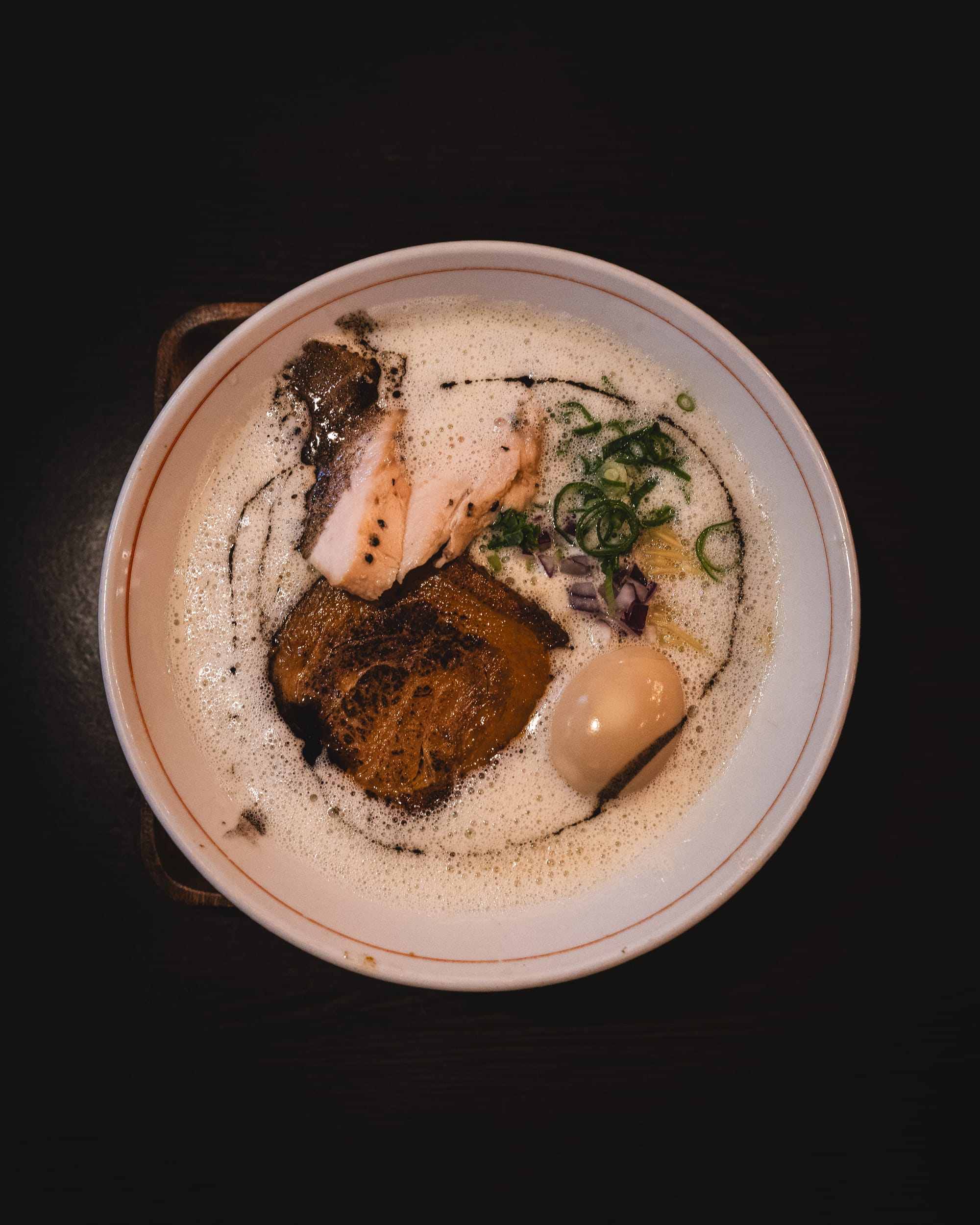 Top down shot of ramen with chicken chashu, chashu, spring onion and egg showing