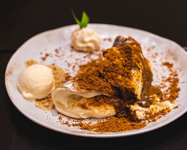 Close up of souffle pancake with biscoff crumbs and a side of ice-cream