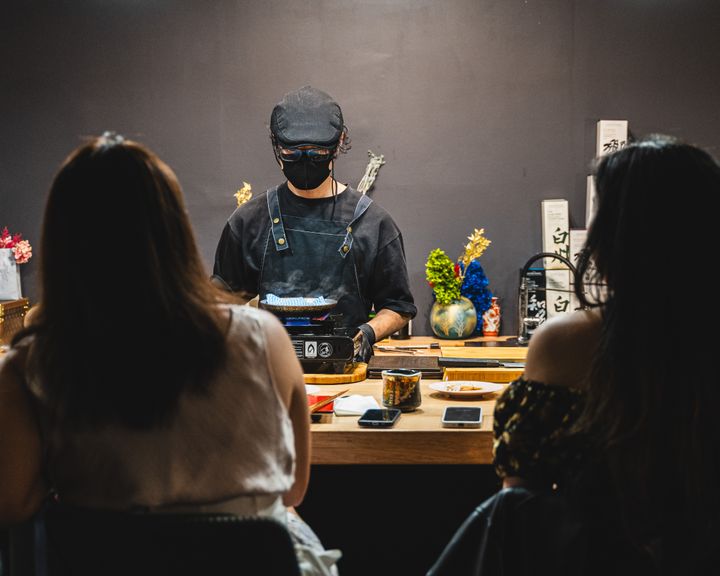 Chef standing behind counter cooking off a portable gas stove